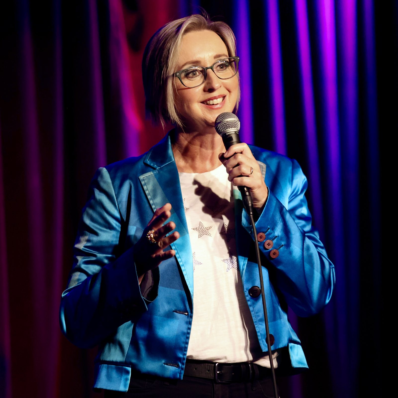 nicola-brown-comedian-on-stage-microphone-blue-satin-blazer